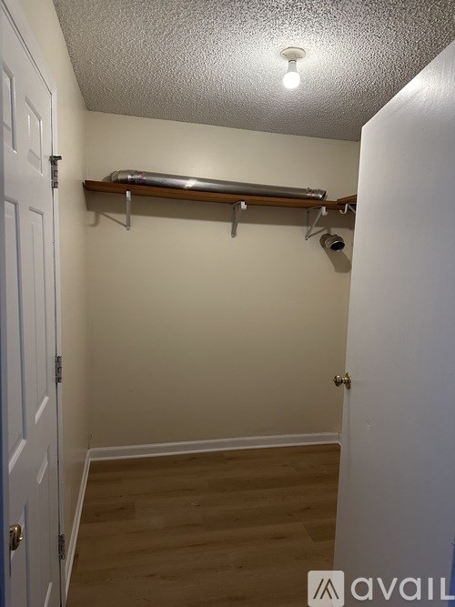 A room with a white door and a white wall with a shelf and a light on the ceiling.