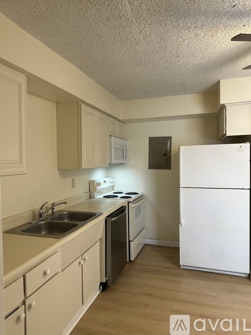 A kitchen with a white refrigerator and white cabinets.