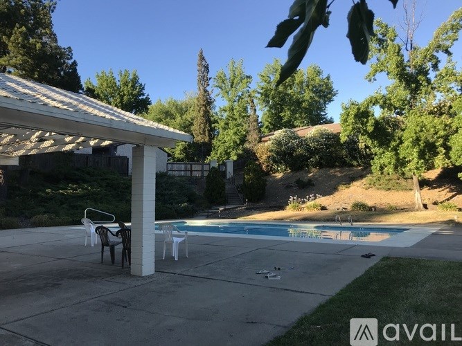 A pool area with a table and chairs under a roof.