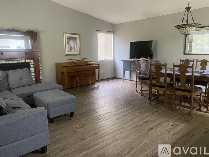 A living room with a grey couch, a wooden desk, and a television.