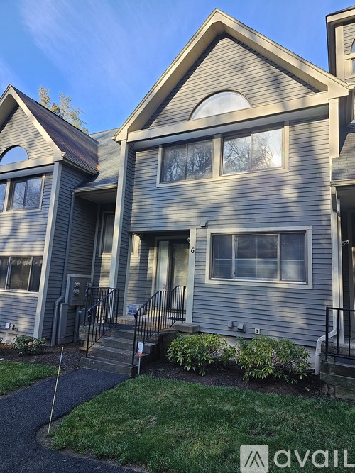 A grey house with a black railing and a small garden in front.