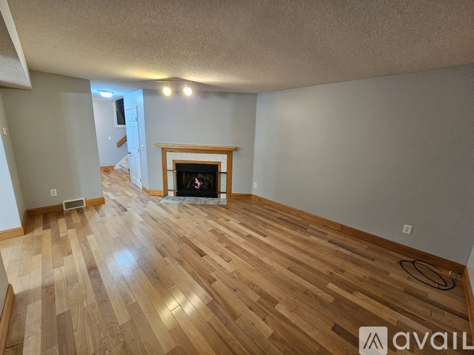 A living room with a fireplace and wooden floors.