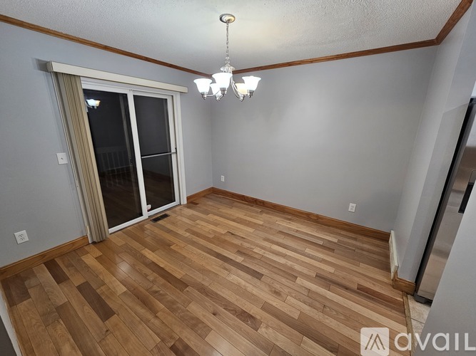 A room with wooden flooring and a chandelier hanging from the ceiling.