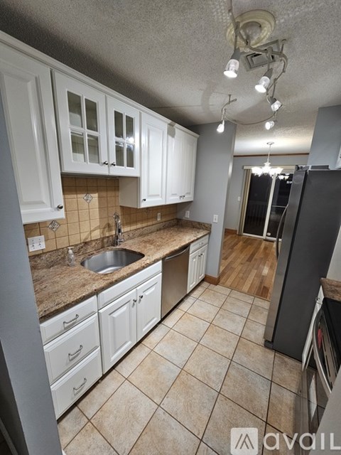 A kitchen with white cabinets and a tiled floor.