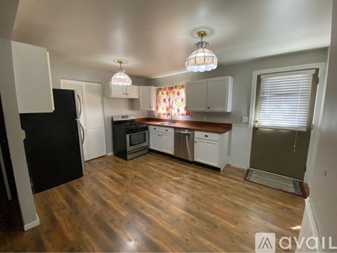 A kitchen with wooden floors and white cabinets.