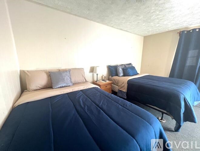 A bedroom with two beds and a nightstand.