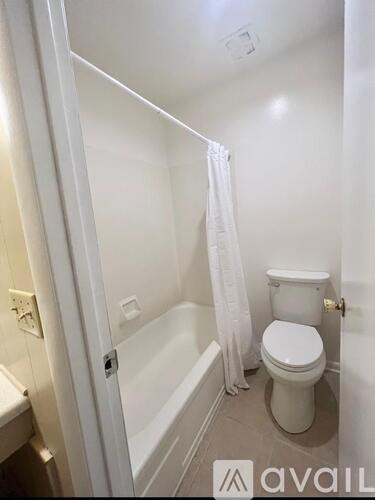 A white toilet in a small bathroom with a white shower curtain.