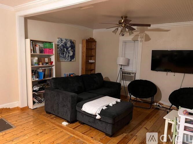A living room with a black couch, a chair, and a television.