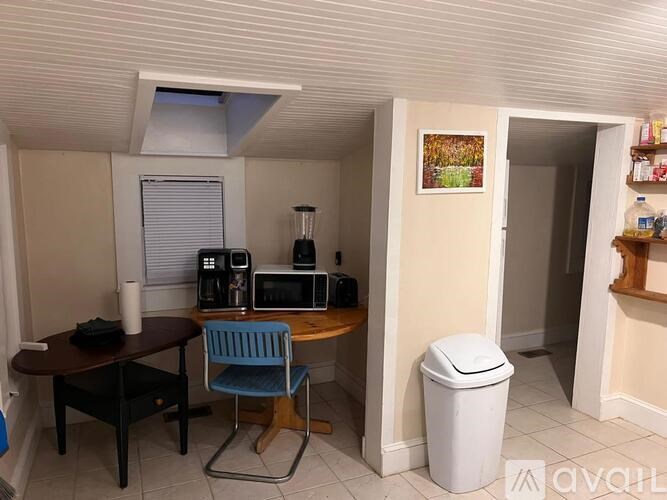 A kitchen area with a table, chairs, and a trash can.