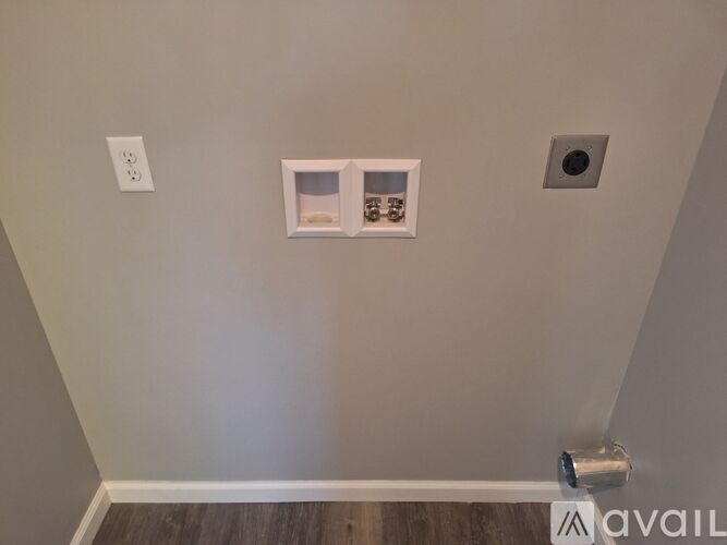 A wall with a white outlet, a white electrical box, and a white vent.
