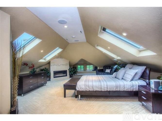 A bedroom with a bed, dresser, and a fireplace.