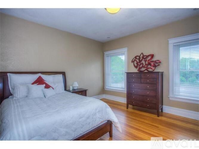 A bedroom with a large bed and a wooden dresser.