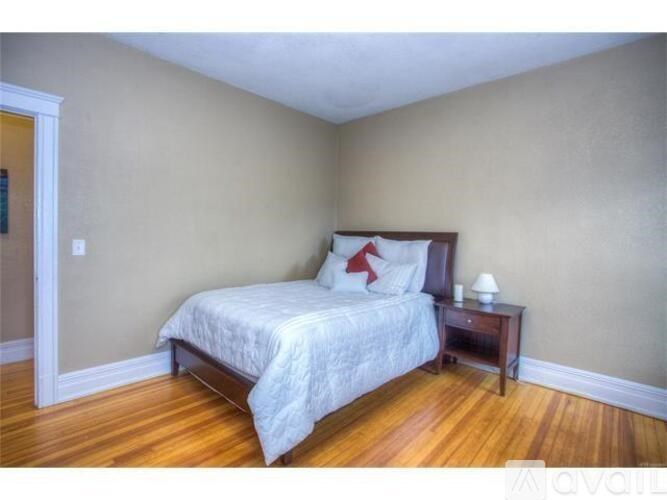 A bedroom with a bed, nightstand, and lamp.