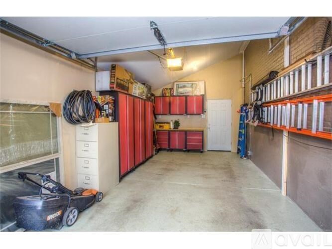 A storage room with red shelving units and a black vacuum cleaner on the floor.