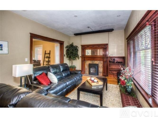 A living room with a black leather couch and a fireplace.