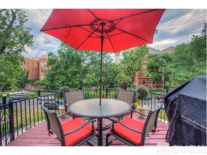 A red umbrella is open over a table on a deck.