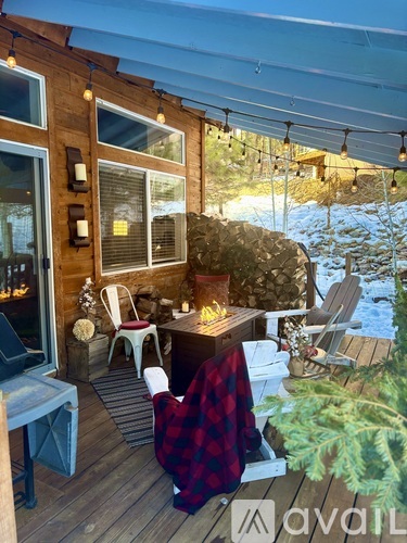 A wooden deck with a table and chairs and string lights.