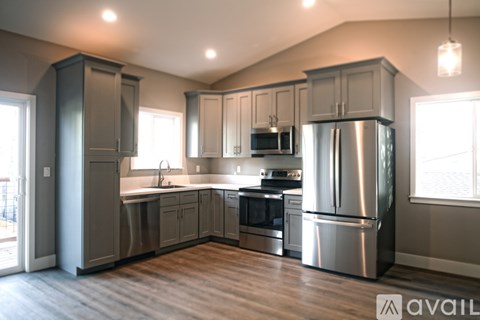 A modern kitchen with a stainless steel refrigerator and wooden flooring.