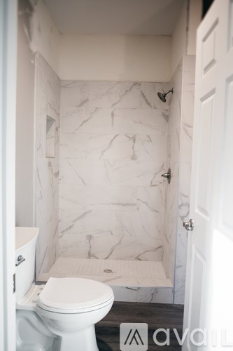 A white toilet in a bathroom with marble wall tiles.