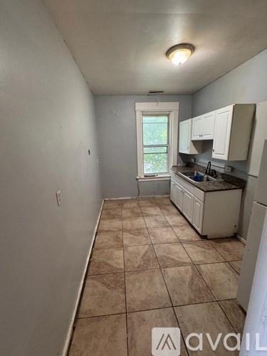 A kitchen with white cabinets and a tiled floor.