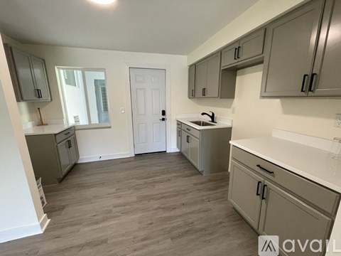 A kitchen with grey cabinets and a white door.