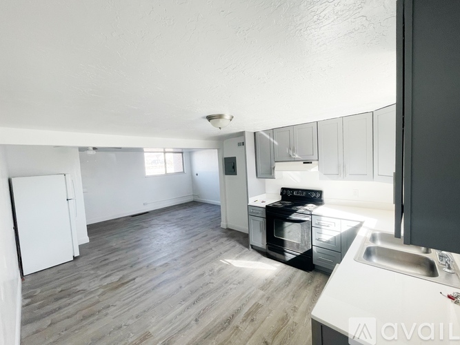A kitchen with a white fridge, stove, and sink.