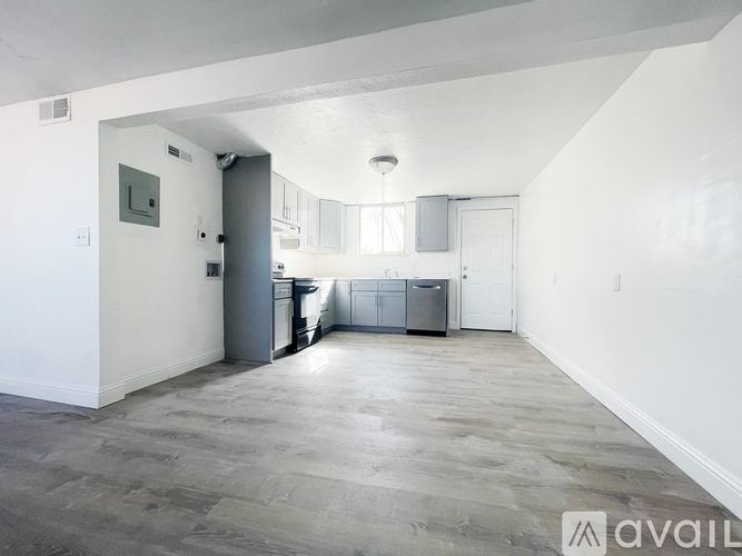 A spacious room with a kitchen area in the background.