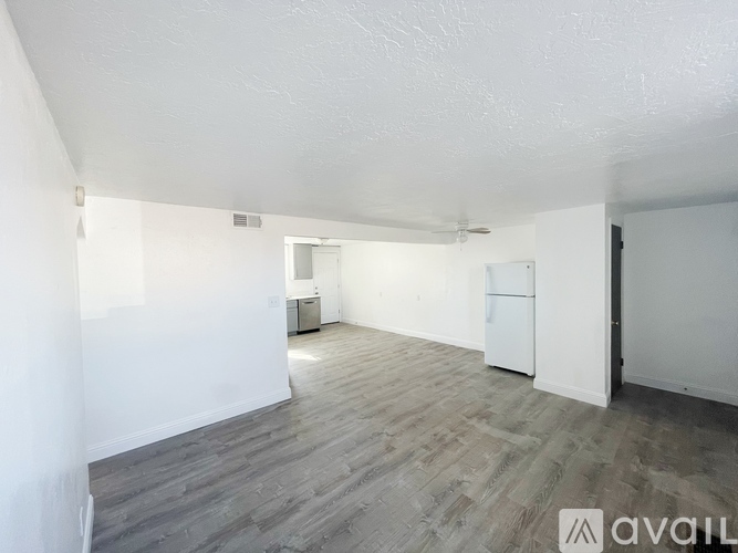 A spacious room with wooden flooring and white walls.