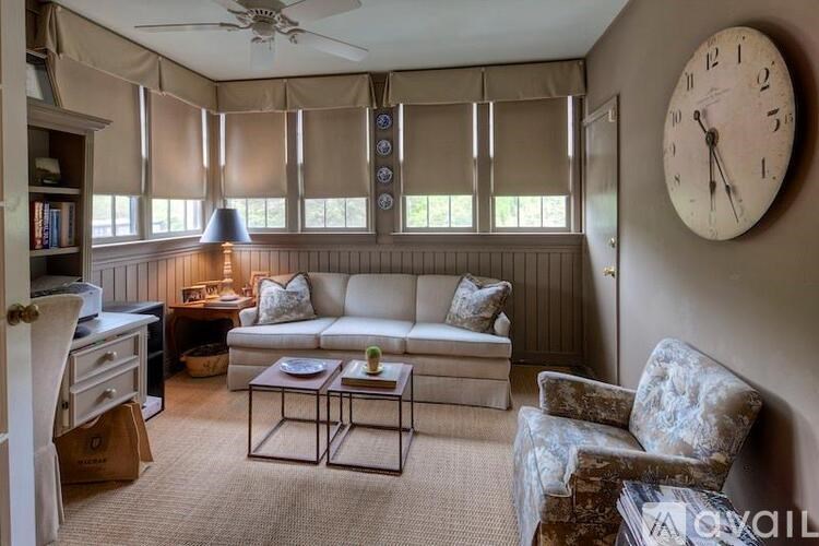 A living room with a couch, chair, and a clock on the wall.