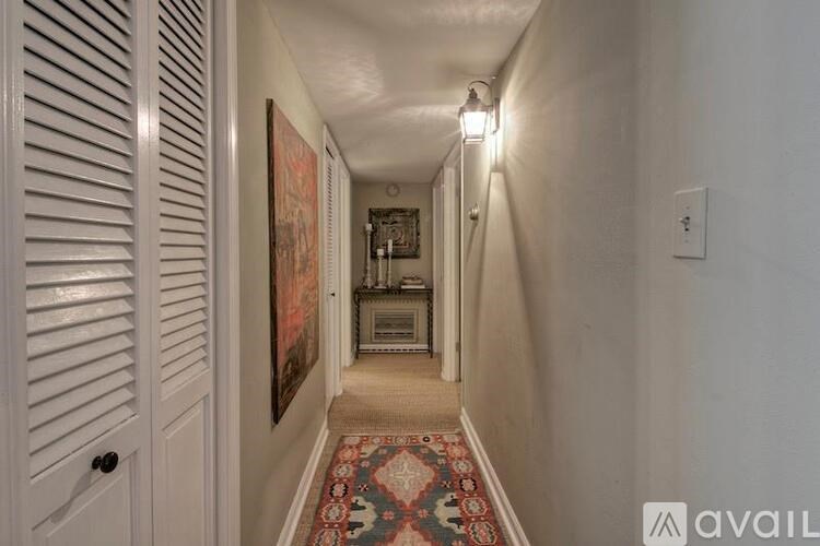 A hallway with a rug and a painting on the wall.