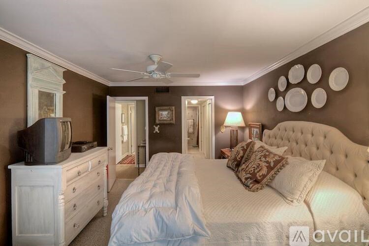 A bedroom with a large bed, a dresser, and a ceiling fan.