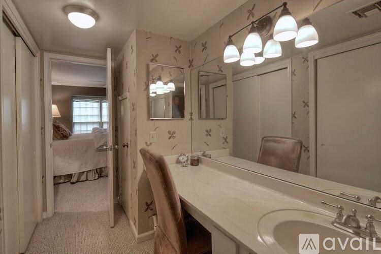 A bathroom with a vanity, a mirror, and a chair.