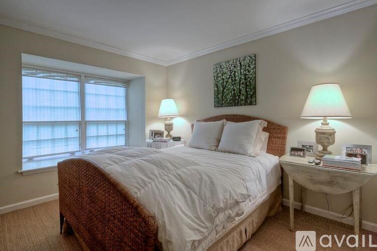 A bedroom with a bed, two lamps, and a painting on the wall.