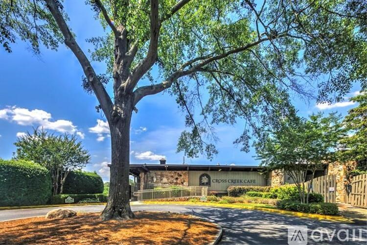 A tree stands in front of a building with the words "Cross Creek Cafe" on it.