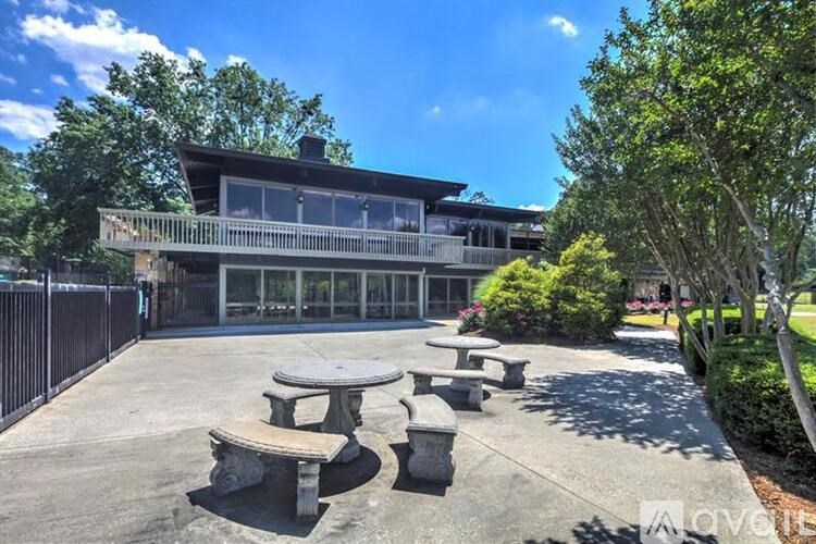 A modern house with a black fence and a concrete patio with a table and chairs.