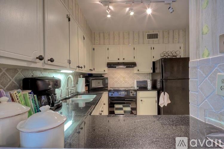 A kitchen with white cabinets and a granite countertop.