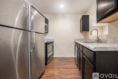 A kitchen with a stainless steel refrigerator and a marble countertop.