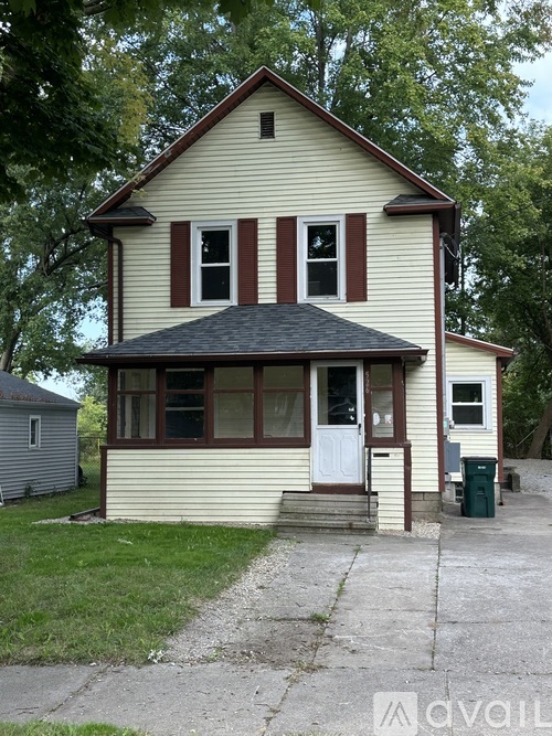 A two-story house with a white door and red shutters.