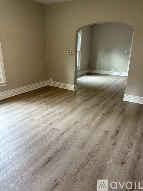 A room with wooden flooring and a white archway.