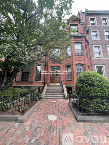 A red brick building with a black gate in front.