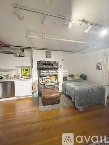 A room with a bed, a couch, and a fridge.