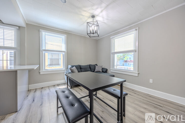A dining area with a black table and bench in a room with light wood flooring.