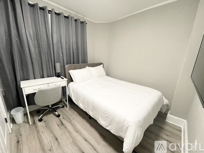 A bedroom with a bed, desk, and chair.