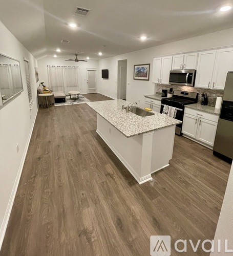 A kitchen with a white countertop and wooden flooring.