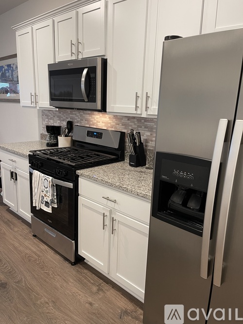 A kitchen with a stainless steel refrigerator and black stove.