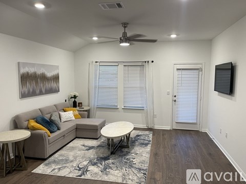 A living room with a grey couch, a rug, a table, and a ceiling fan.