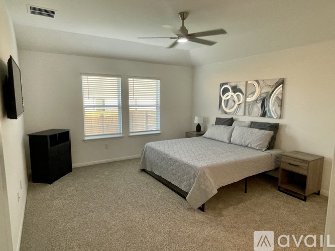 A bedroom with a bed, a ceiling fan, and a window with blinds.