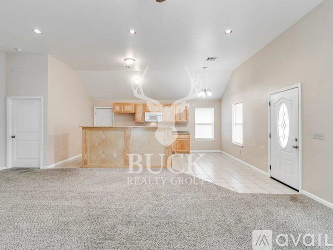 A spacious room with a carpeted floor and a ceiling fan, currently under construction with exposed wooden beams and a framed doorway.