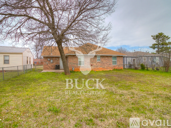 A grassy area with a tree and a house in the background with the words "BUCK REALTY GROUP" overlaid.