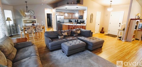 A living room with a large couch and a kitchen in the background.